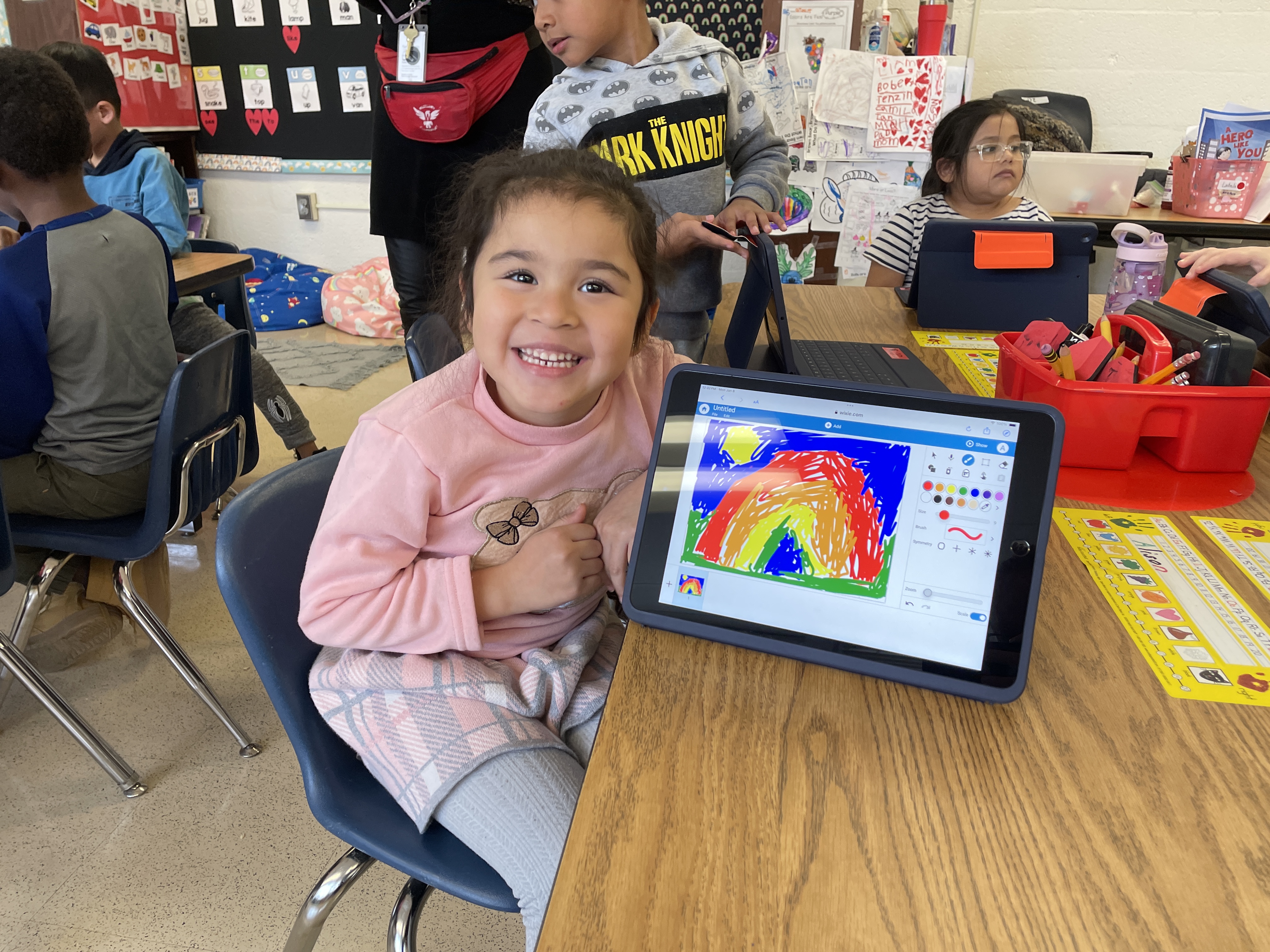 Kindergarten student proudly shows off the rainbow she drew in Wixie
