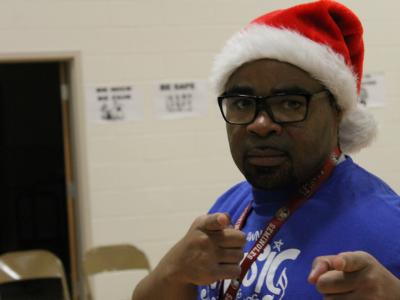 Music teacher in Santa hat pointing at camera
