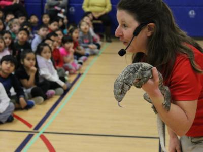 Handler leans in to show students lizard