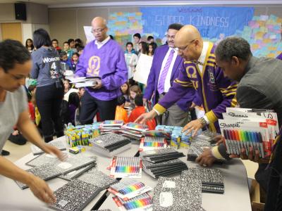 Omega Psi Phi setting out gifts of school supplies