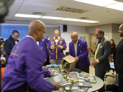 Omega Psi Phi pouring composition books onto supply table