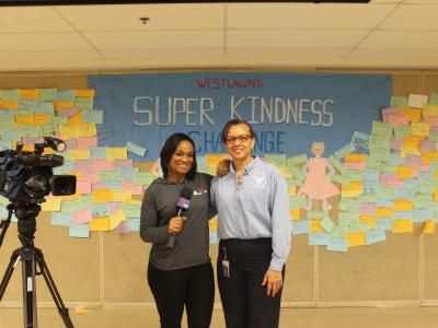 Anchor Green and Mrs. Ferguson pose in front of Super Kindness Wall.