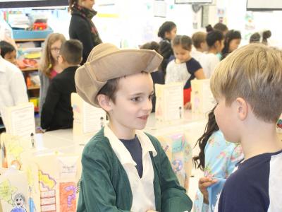 Boy in tricorn hat shakes hand with a student visiting the museum