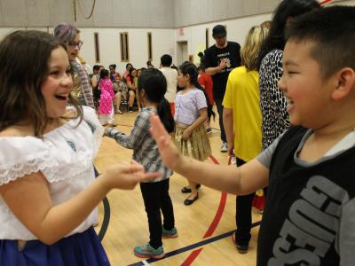 Two students giggle as they practice the hand slapping dance
