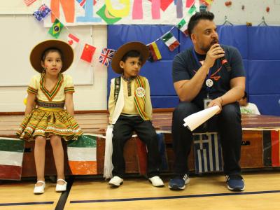 Mr. Sanchez sits with two young dancers before they perform